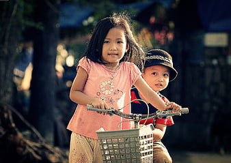 Two young children riding a bicycle together outdoors