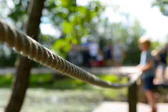 Close-up of thick rope with blurred children playing outdoors