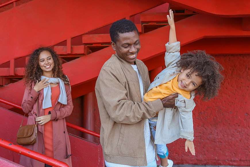 Happy family of three smiling on red stairs
