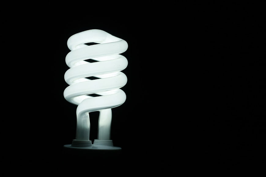 Illuminated CFL Light Bulb on Black Background