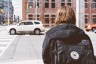 Woman with Backpack Waiting at City Street Crossing