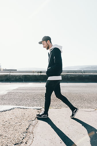 Young man walking on concrete road in streetwear