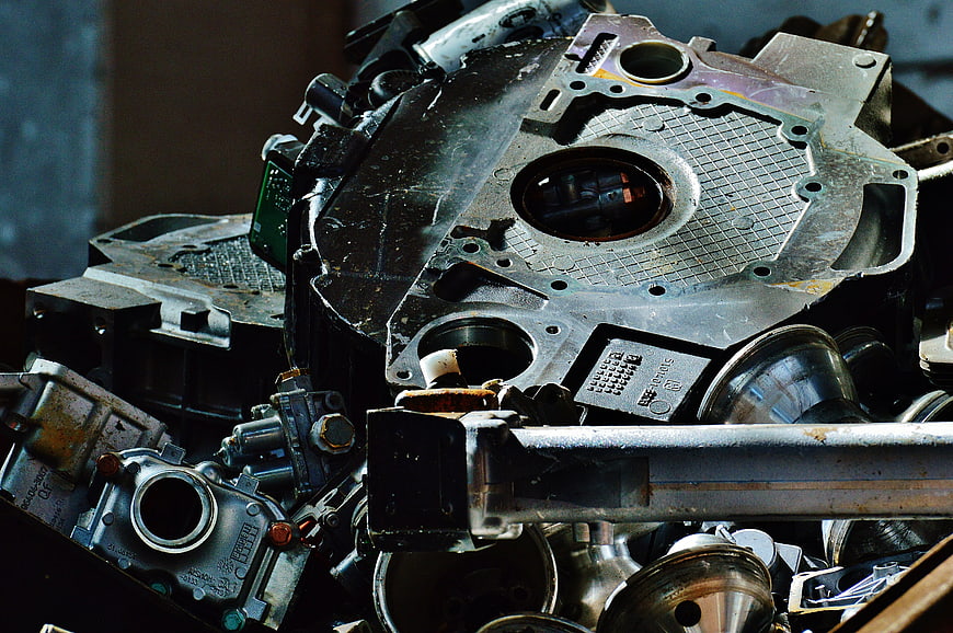 Close-up of scrap metal engine parts and pistons in junkyard