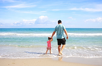 Father and Daughter Walking Hand in Hand on Beach