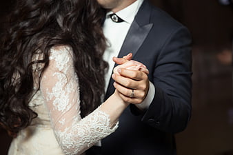 Close-up of bride and groom holding hands while dancing at wedding