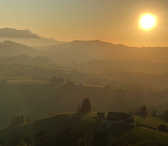 Golden sunrise over misty mountain valley with farmhouses