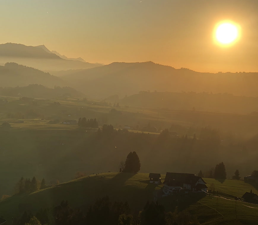Golden sunrise over misty mountain valley with farmhouses