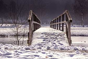 Snowy Wooden Bridge Over Frozen River in Winter