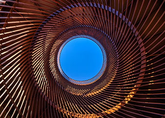 Abstract spiral metal structure looking up at blue sky