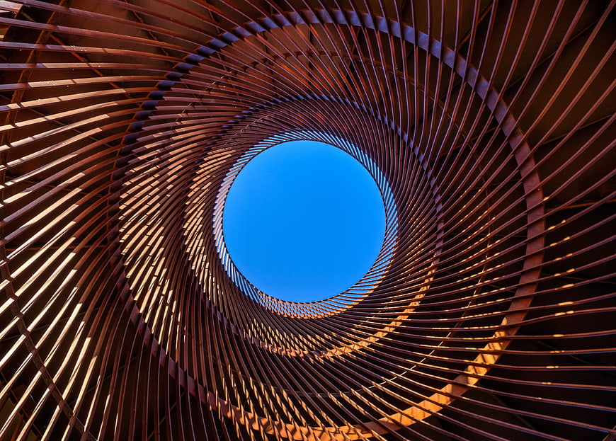 Abstract spiral metal structure looking up at blue sky