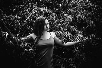 Black and white portrait of a woman standing in dense foliage