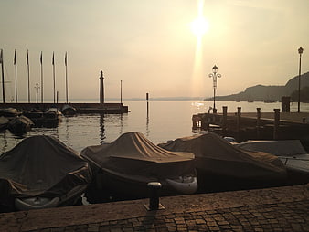 Covered boats in harbor at sunset with calm lake water