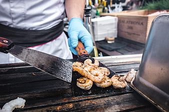 Chef grilling seasoned shrimp on outdoor barbecue
