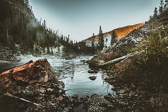 Misty river valley with sunrise light on forested hills