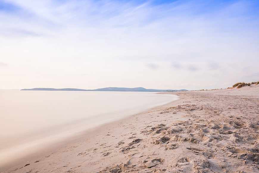 Serene Long Exposure Beach with Smooth Water and Sandy Shore