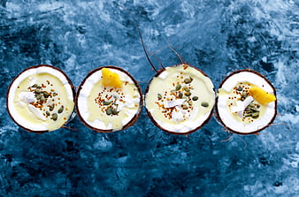 Top view of four coconut bowls with creamy dessert and toppings