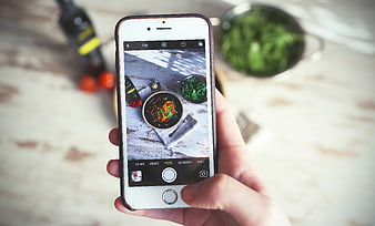 Hand holding smartphone photographing food dish