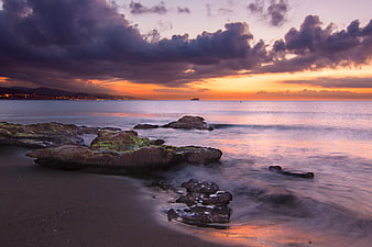 Dramatic Sunset Over Rocky Coastline with Silky Ocean Waves