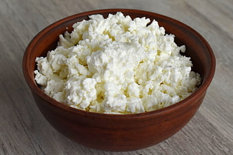 Fresh cottage cheese in a rustic wooden bowl on a light table