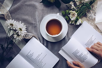 Flat lay of tea, poetry books, and flowers on gray linen