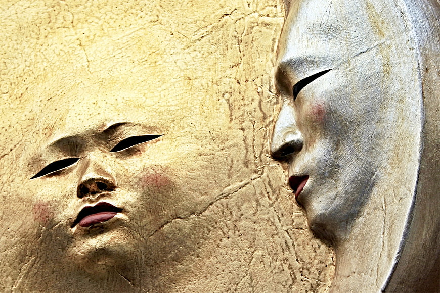Close-up of textured gold and silver sun and moon masks