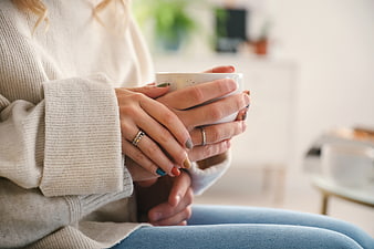 Couple holding coffee mug together in cozy sweater