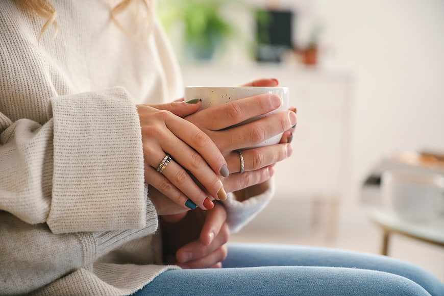 Couple holding coffee mug together in cozy sweater