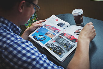 Man reading car magazine with coffee at table