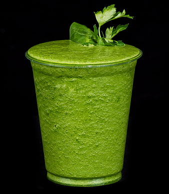 Vibrant green detox smoothie in plastic cup with parsley garnish