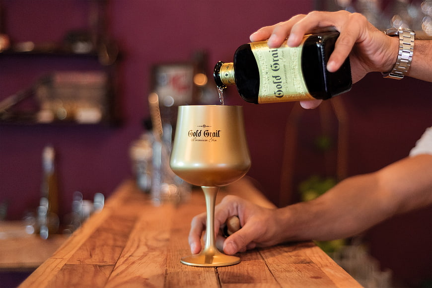 Bartender pouring Gold Grail liqueur into golden glass