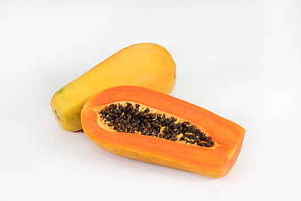 Fresh ripe papaya fruit cut in half on white background
