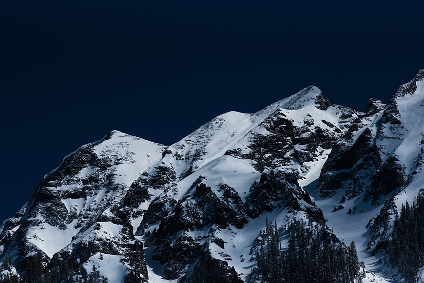 Snowy Mountain Peaks Against Deep Blue Night Sky