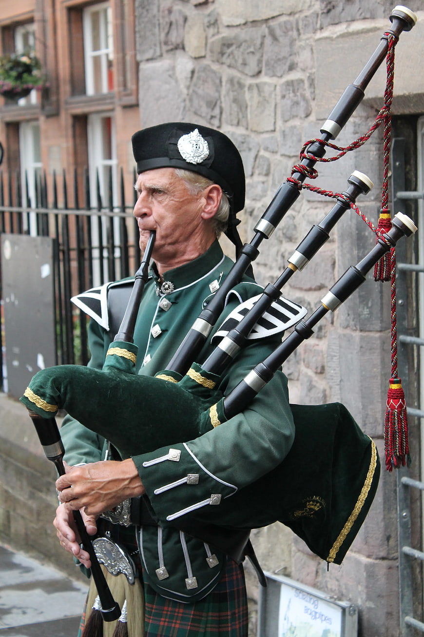 Scottish Bagpiper in Traditional Green Uniform Playing