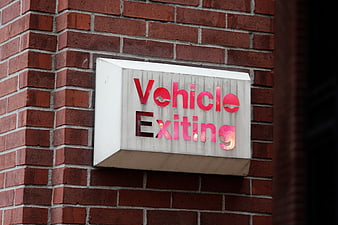 Red Vehicle Exiting Sign on Brick Wall