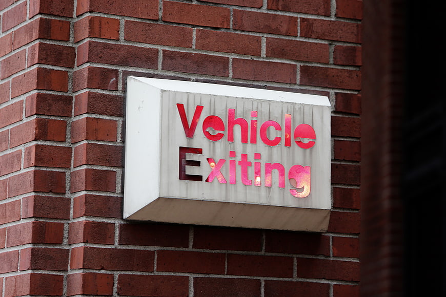 Red Vehicle Exiting Sign on Brick Wall