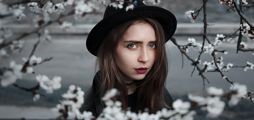 Woman in Black Hat with Red Lips Among White Blossoms