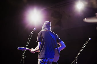 Musician playing guitar on stage with purple spotlight