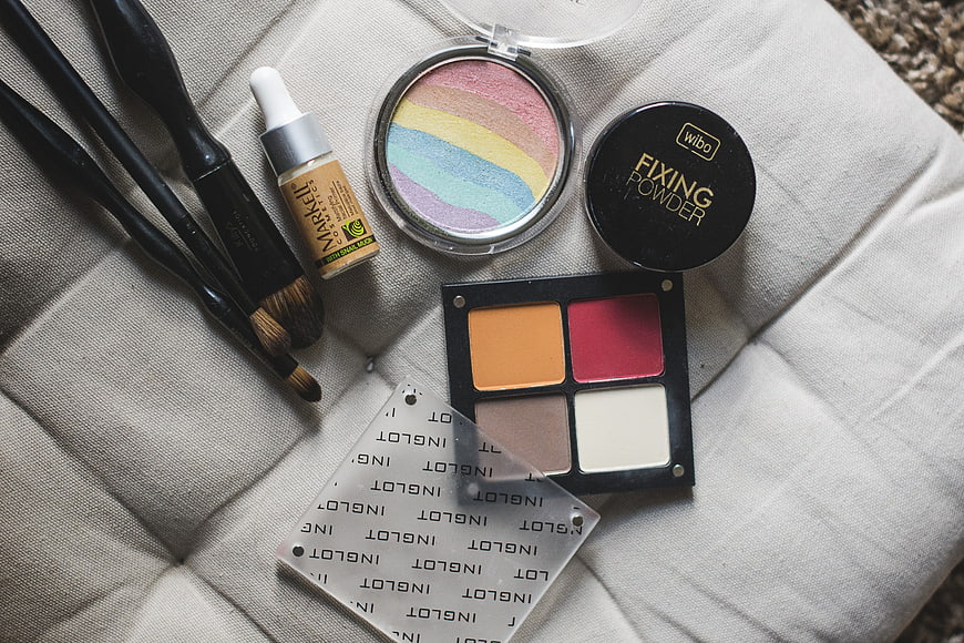 Flat lay of makeup brushes, eyeshadow palette, and setting powder