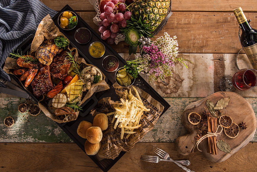 Overhead view of rustic BBQ feast with wine and spices