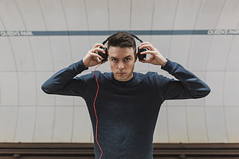 Young man putting on headphones in subway station
