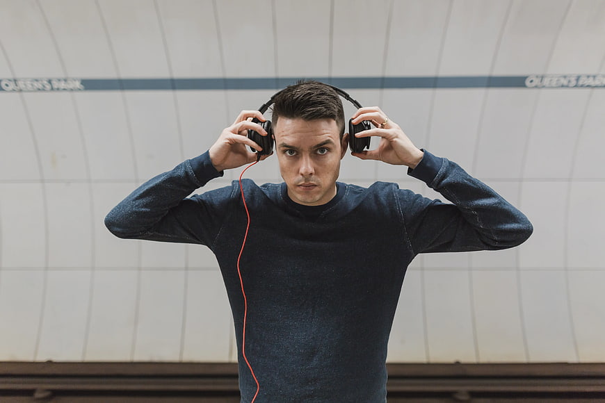 Young man putting on headphones in subway station