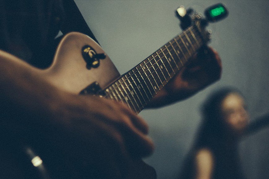 Close-up of musician tuning electric guitar on stage