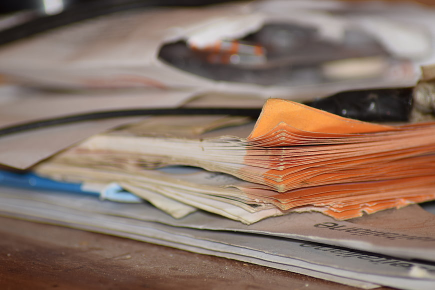 Close-up of stacked orange and white paper documents on wooden desk