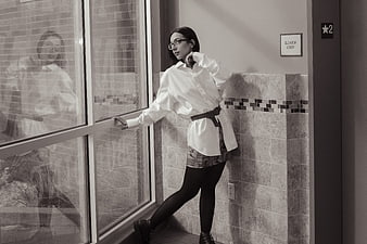 Stylish woman in white shirt posing by window in black and white