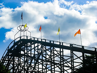 Wooden Rollercoaster Silhouette Against Blue Sky and Clouds