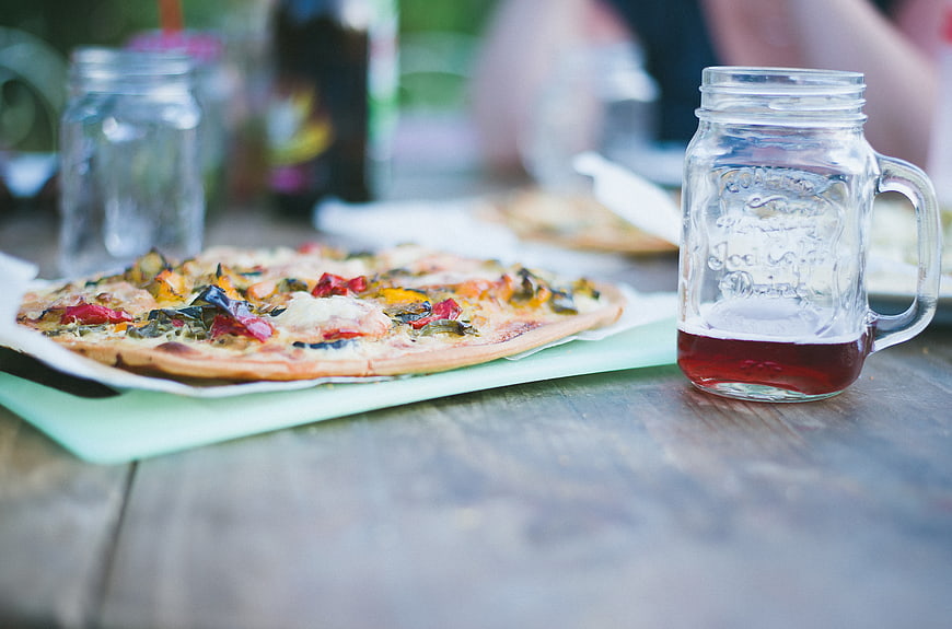 Gourmet pizza and iced tea in mason jar on wooden table