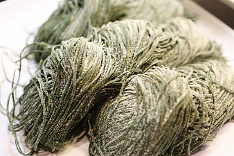 Close-up of fresh green spinach pasta nests on white surface