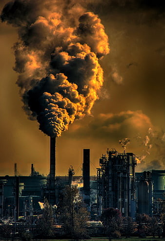 Industrial smokestack emitting thick smoke at sunset