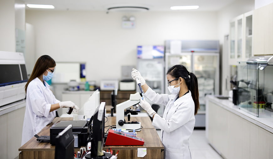Two female scientists working with laboratory equipment in a modern medical facility