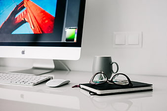 Modern white workspace with iMac, notebook, and glasses